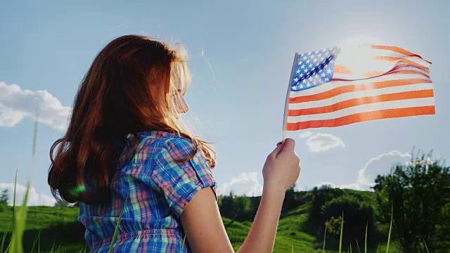 阳光下挥舞着美国国旗的年轻女子视频素材