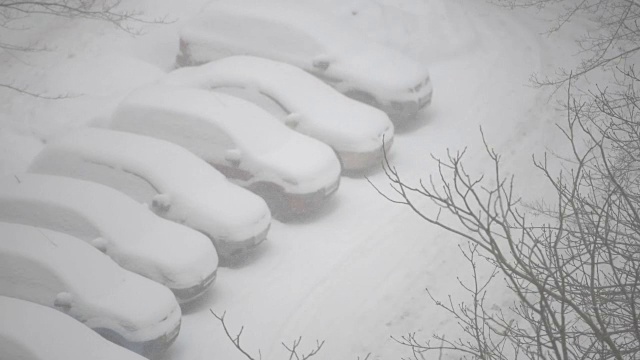 下雪时，住宅区停车场上的汽车被雪覆盖视频素材