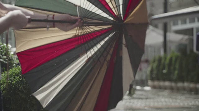 城市街道上的雨天背景。真正的时间。年轻女孩拿着五颜六色的雨伞。人们在雨中带着雨伞上下班。模糊的散景。自然背景视频素材