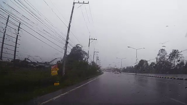 透过汽车挡风玻璃看路，有雨滴，在雨中行驶。视频素材