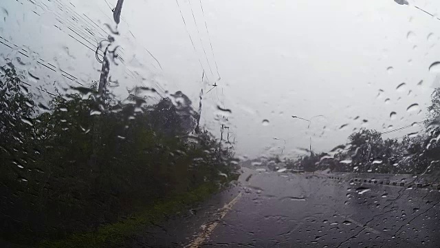 透过汽车挡风玻璃看路，有雨滴，在雨中行驶。视频素材