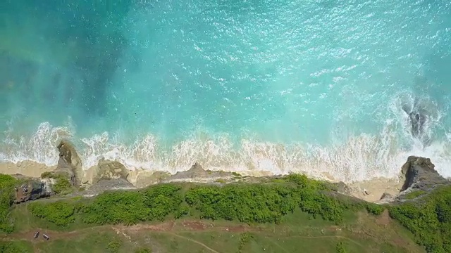 AERIAL:泡沫状的海浪冲刷着巴厘岛岩石悬崖下的白色沙滩视频素材