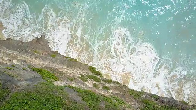 天线:荡漾的海水冲走了岩石悬崖下梦幻般的海滩上的沙子视频素材