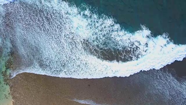 空中从上到下，在晶莹剔透的海面上，泡沫状的海浪拍打着珊瑚礁视频素材