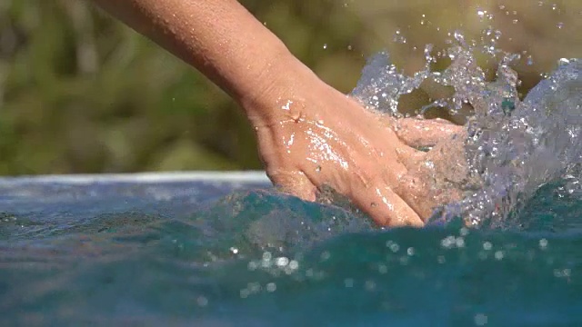 慢动作人的手滑过水面溅水花池视频素材