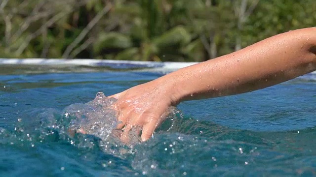 靠近女性的手触摸水面溅水花在游泳池和温泉度假村视频素材