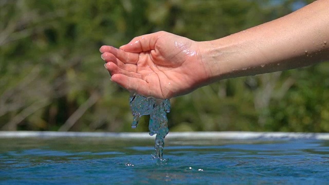 慢动作细节手玩水，水滴落入水池视频素材