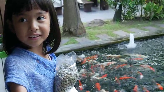 亚洲女孩在池塘里喂鲤鱼视频素材