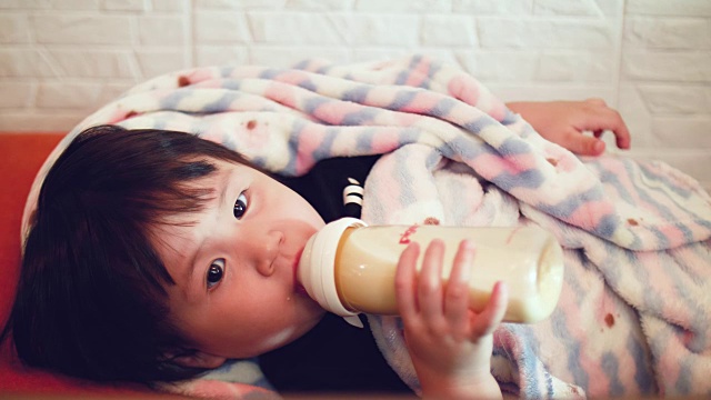 亚洲女婴用奶瓶喝牛奶视频素材