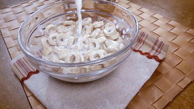 脆燕麦片在碗里，早餐美味的牛奶。慢动作旋转跟踪镜头。视频素材