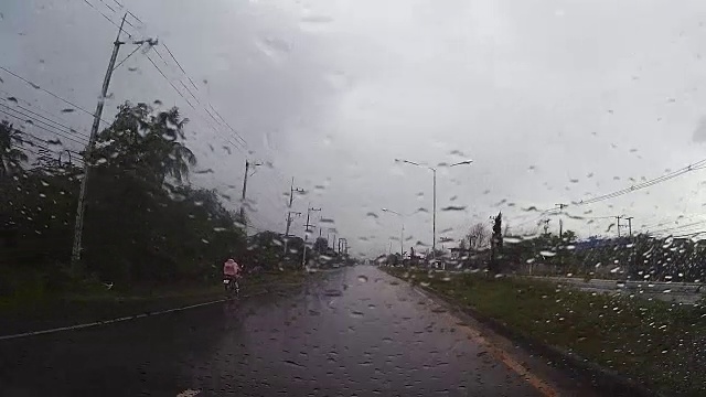 透过汽车挡风玻璃看路，有雨滴，在雨中行驶。视频素材