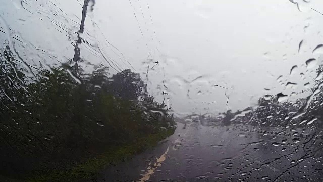 透过汽车挡风玻璃看路，有雨滴，在雨中行驶。视频素材