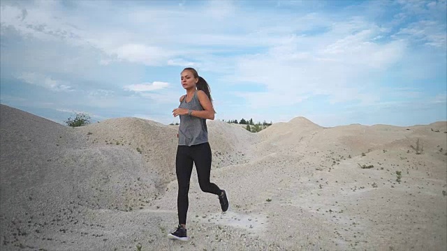 一位身材姣好的年轻女子白天积极地沿着沙滩公园跑步视频素材