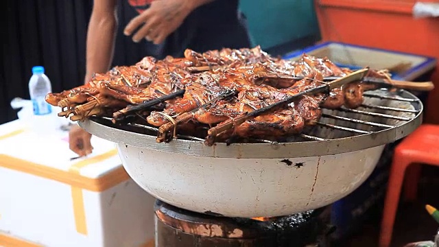 男子在泰国市场做烤鸡。视频素材