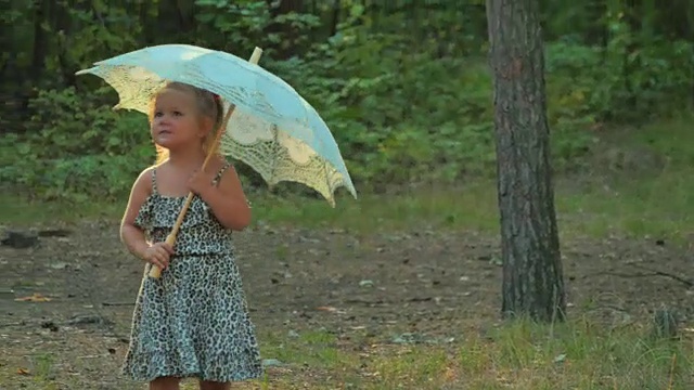 可爱的小女孩拿着雨伞在森林里散步视频素材