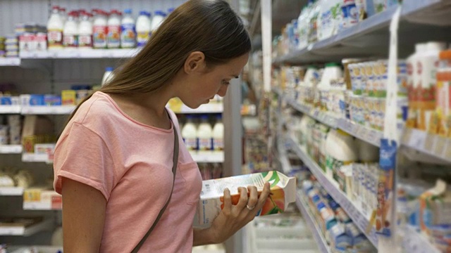 在购物中心的食品杂货店里，一位女士在冰箱里挑选乳制品视频素材