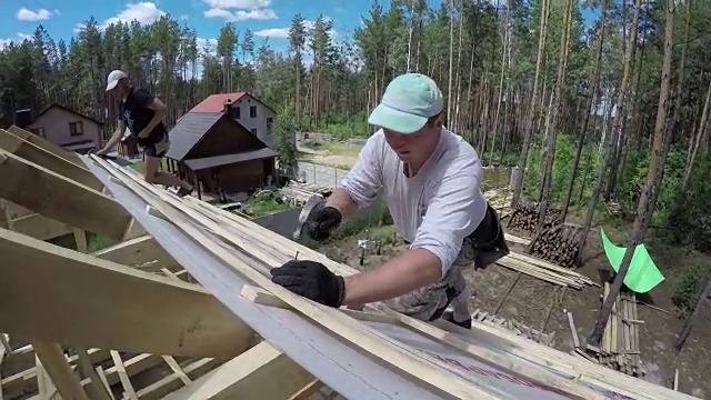 屋顶工人正在把钉子钉进屋顶的木板里。视频素材