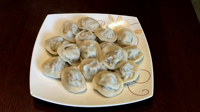 盘子里装着饺子。桌上有一盘热的自制饺子。喷射蒸汽视频素材