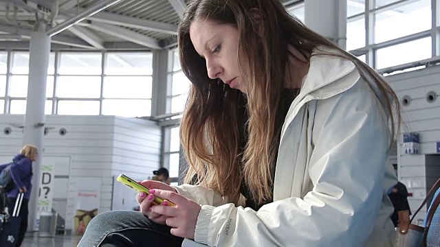 年轻漂亮的女人在机场等飞机的时候发短信视频素材