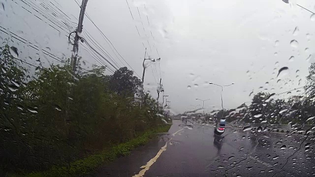 透过汽车挡风玻璃看路，有雨滴，在雨中行驶。视频素材