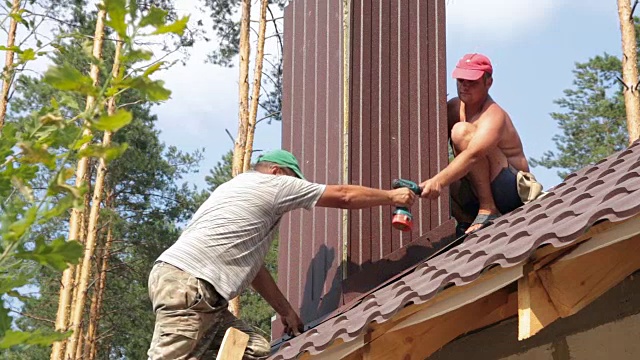 屋顶工人在靠近烟囱的屋顶上工作。视频素材