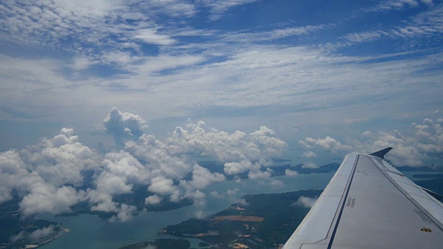 从飞机窗口俯瞰机翼和引擎。飞机是在云和天空之上飞行的交通或旅行的概念。视频素材