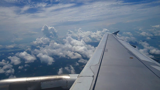 从飞机窗口俯瞰机翼和引擎。飞机是在云和天空之上飞行的交通或旅行的概念。视频素材