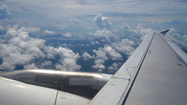 从飞机窗口俯瞰机翼和引擎。飞机是在云和天空之上飞行的交通或旅行的概念。视频素材