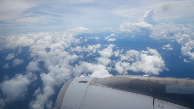 从飞机窗口俯瞰机翼和引擎。飞机是在云和天空之上飞行的交通或旅行的概念。视频素材