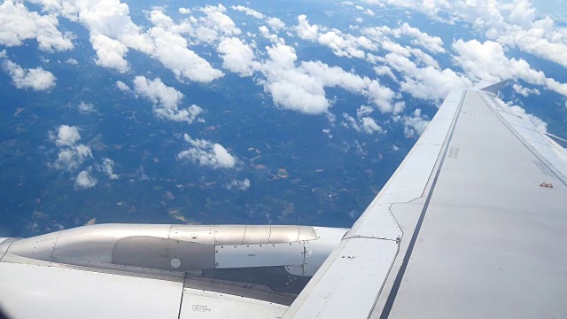 从飞机窗口俯瞰机翼和引擎。飞机是在云和天空之上飞行的交通或旅行的概念。视频素材