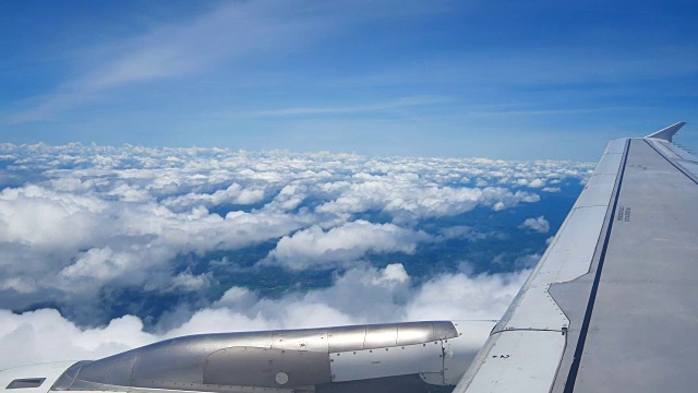 从飞机窗口俯瞰机翼和引擎。飞机是在云和天空之上飞行的交通或旅行的概念。视频素材