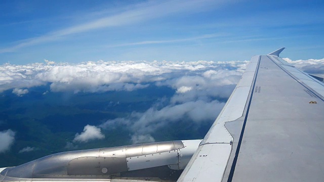 从飞机窗口俯瞰机翼和引擎。飞机是在云和天空之上飞行的交通或旅行的概念。视频素材