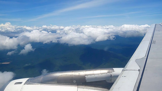 从飞机窗口俯瞰机翼和引擎。飞机是在云和天空之上飞行的交通或旅行的概念。视频素材