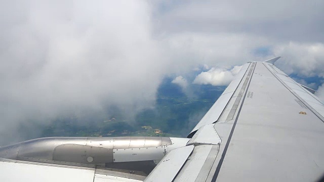 从飞机窗口俯瞰机翼和引擎。飞机是在云和天空之上飞行的交通或旅行的概念。视频素材