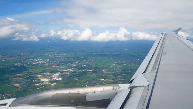 从飞机窗口俯瞰机翼和引擎。飞机是在云和天空之上飞行的交通或旅行的概念。视频素材