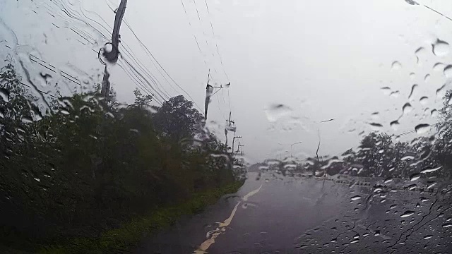 透过汽车挡风玻璃看路，有雨滴，在雨中行驶。视频素材