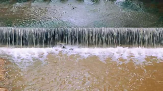 连续的水运动场景中的堰或坝减缓了河水的流动。泰国有新鲜的绿色区域。视频素材