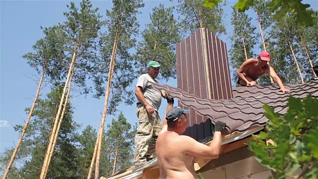 屋顶工人在靠近烟囱的屋顶上工作。视频素材