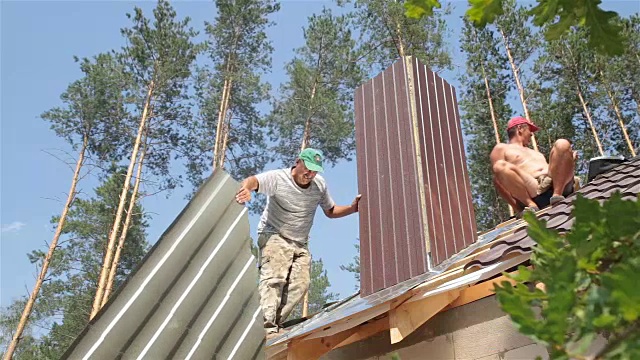 屋顶工人在靠近烟囱的屋顶上工作。视频素材