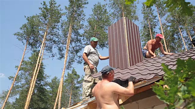 屋顶工人在靠近烟囱的屋顶上工作。视频素材