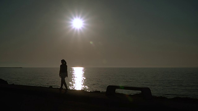 日落时分，一个女孩在海边散步。视频下载