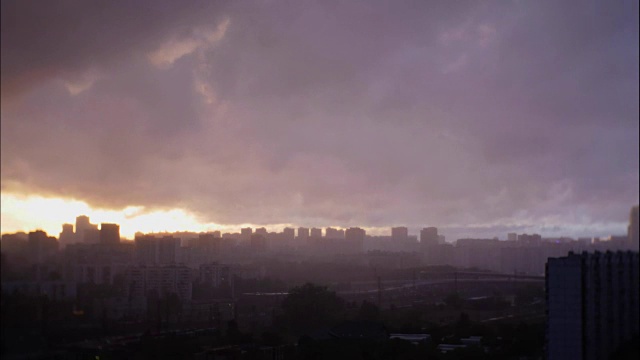 日落时城市上空乌云密布。在落日的背景下下起了雨视频素材