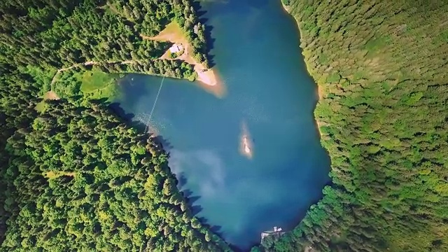 空中飞过美丽的山脉和森林，绕着一个不可思议的蓝色湖泊的轴线旋转视频素材