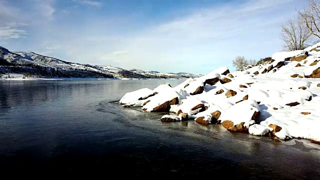 低空飞行在冰冻的水和被雪覆盖的岩石上视频素材