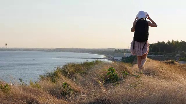 旅行者女人搭便车在阳光明媚的海滩和步行。年轻快乐的背包女寻找一个骑在一个阳光照耀的乡村道路开始旅程视频素材