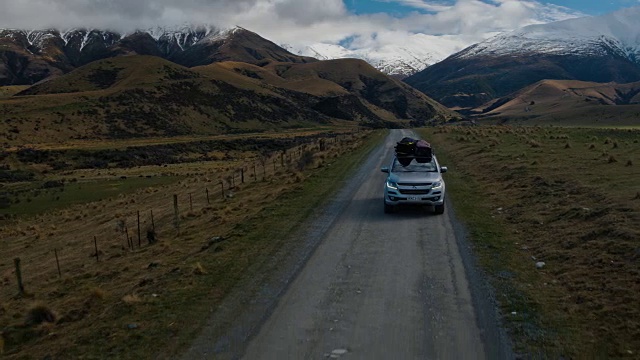 鸟瞰图SUV驾驶在沙漠向雪山山峰在新西兰视频素材