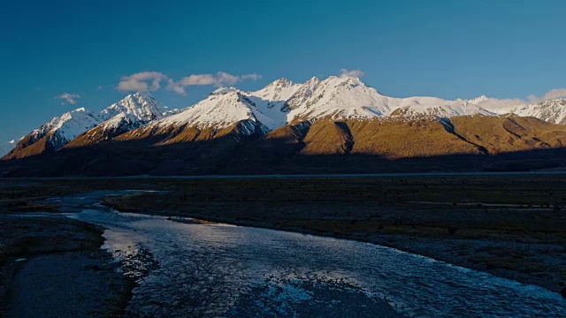 鸟瞰图飞过雪融化的河流，朝向新西兰雪山的山峰视频素材