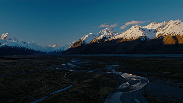 鸟瞰图飞过雪融化的河流，朝向新西兰雪山的山峰视频素材