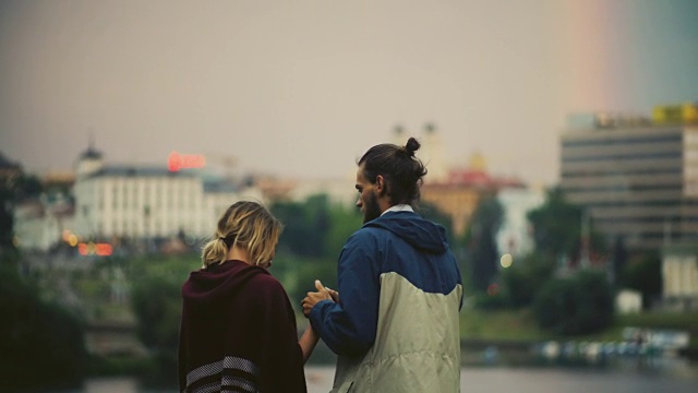 快乐的夫妇看城市全景在日落的背面。男人拥抱女人，享受夜晚的市中心视频素材