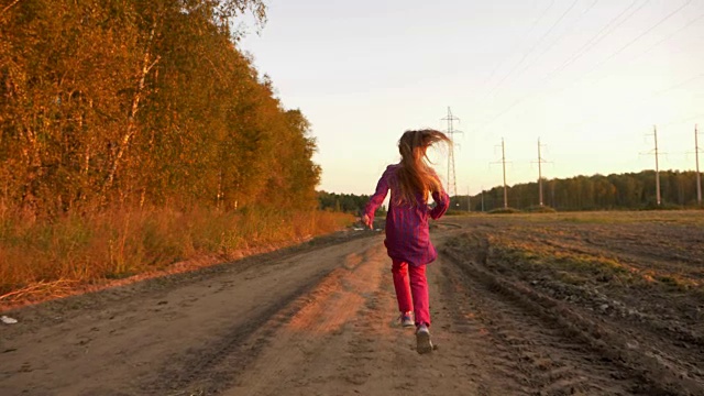 年轻的白人女孩跳跑在肮脏的乡村公路上。秋天的风景路和金色的树叶视频素材